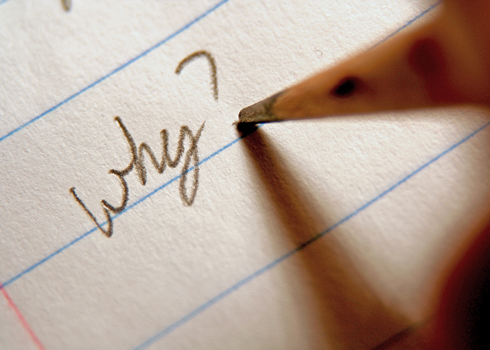 A pencil writing "why?" on a piece of lined paper.