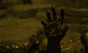 A very dark image of a hand covered in tar reaching out of a pool of tar as if for help or in it's last spasms.