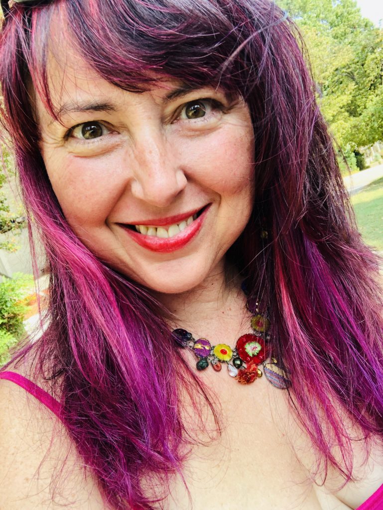 Photo of Nookie: smiling woman with red and purple hair. 