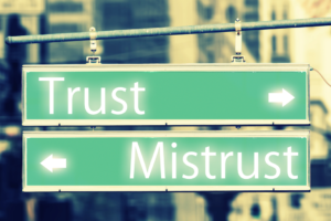 Two street signs. One say "trust" pointing in one direction. The other says "mistrust," and points in the opposite direction.